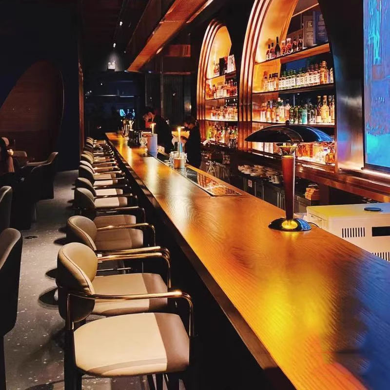 Modern bar with high-end counter seating and shelves full of liquor, designed for a stylish and sophisticated dining experience.