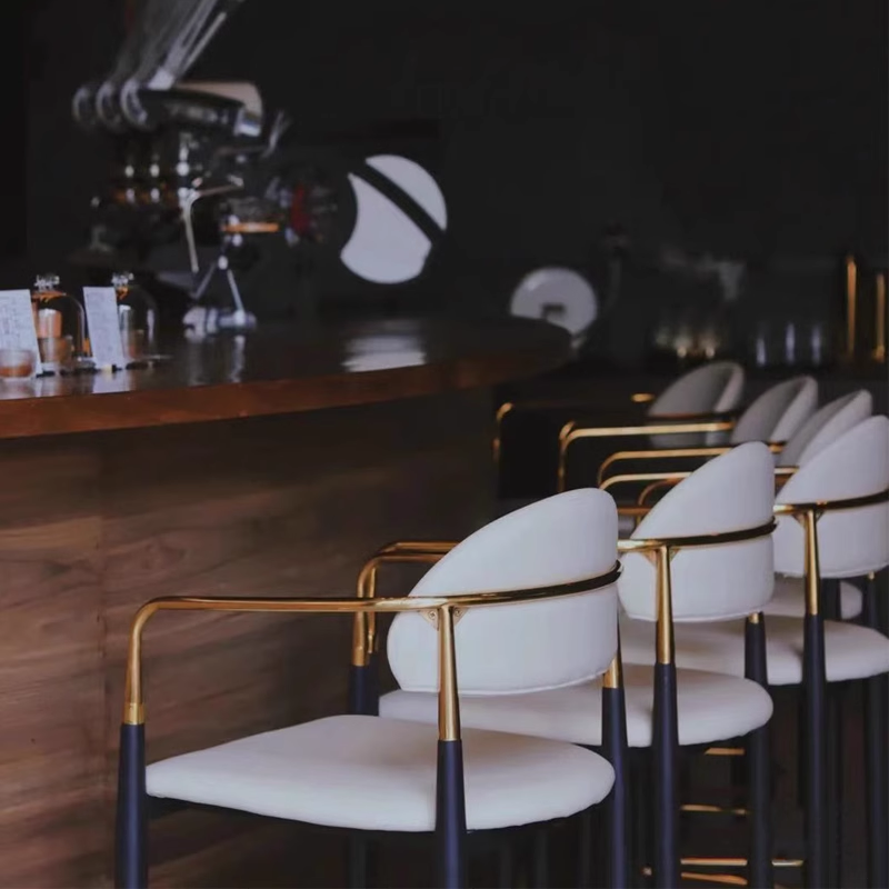 Close-up of white bar stools with gold armrests and legs, creating a luxurious seating area.