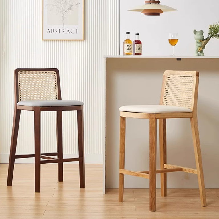 Dark wood bar stool with a woven cane backrest and cushioned seat, placed beside a light-colored bar counter.