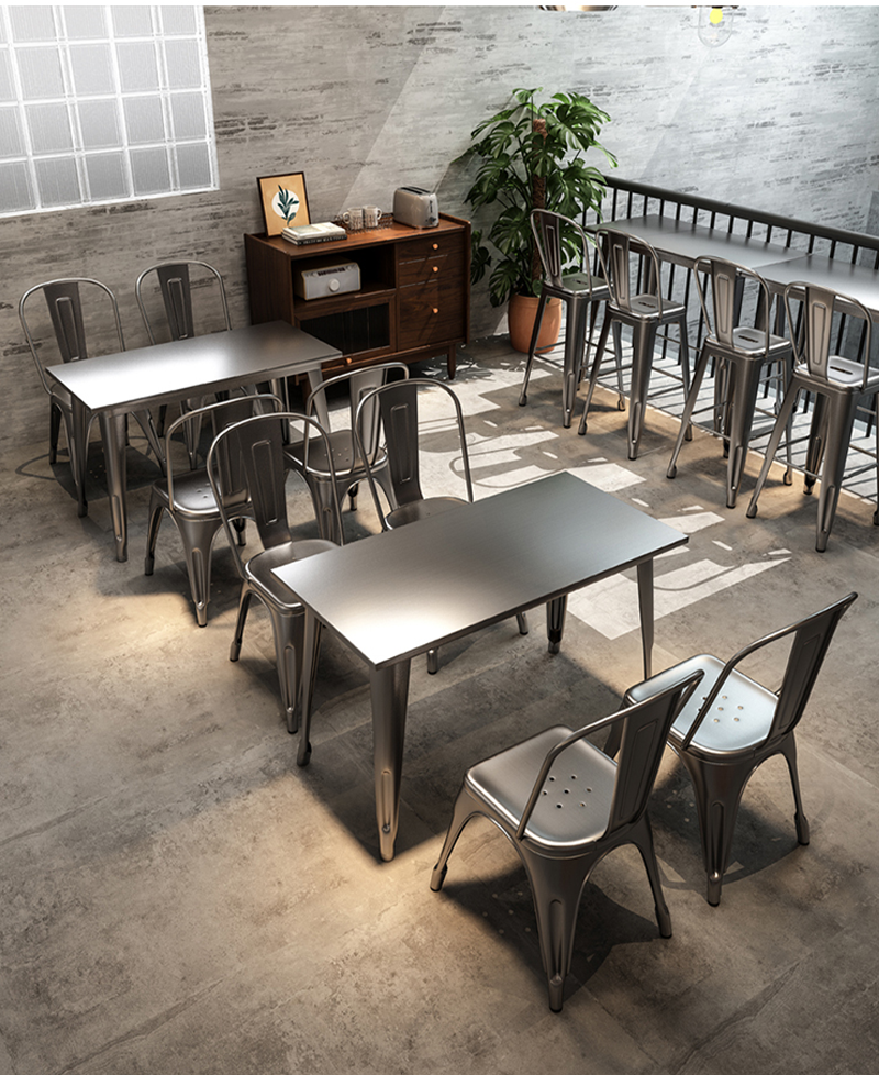 Industrial-style dining area with steel tables and chairs, featuring a minimalistic design and durable materials for modern restaurant use.