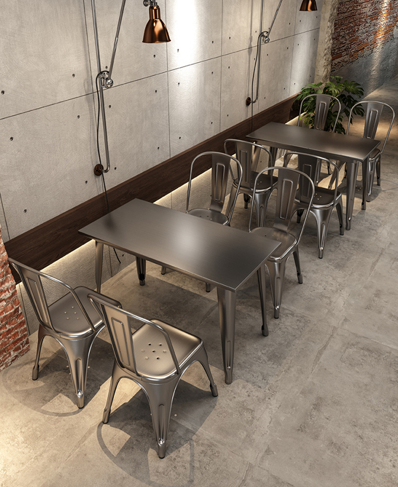 A rustic wooden bar table with metal stools in a cozy, urban restaurant setting.