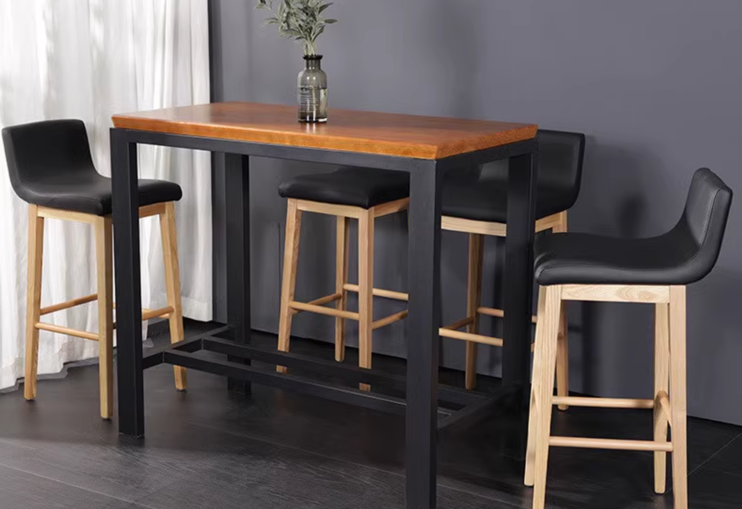 A modern bar table with a wooden top and black metal frame, accompanied by four black leather stools with wooden legs, ideal for home or restaurant use.