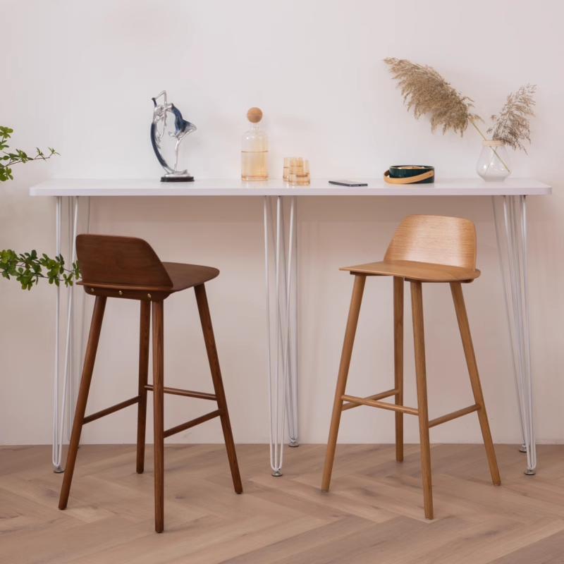 Two modern wooden barstools paired with a white table in a minimalist interior.