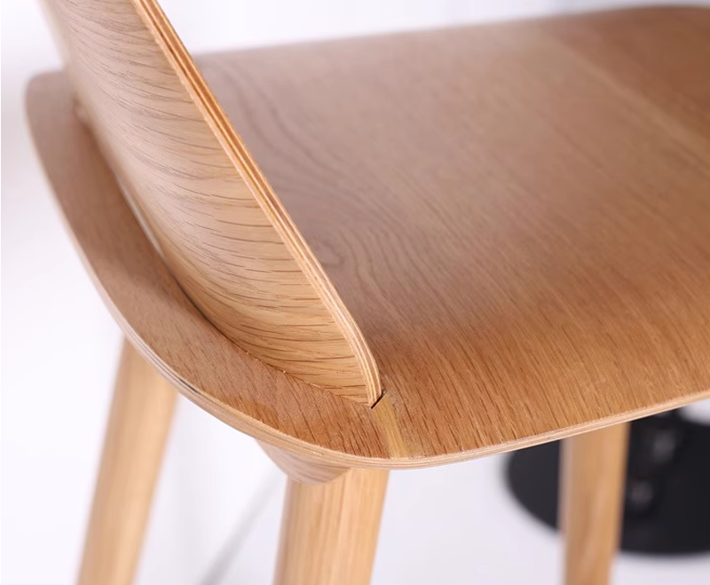 Close-up of oak wood chair backrest corner showing seamless craftsmanship and natural wood texture.