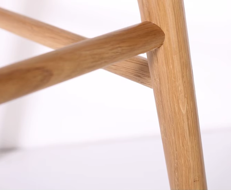 Close-up of oak wood chair crossbar support showing strong connection and smooth texture.