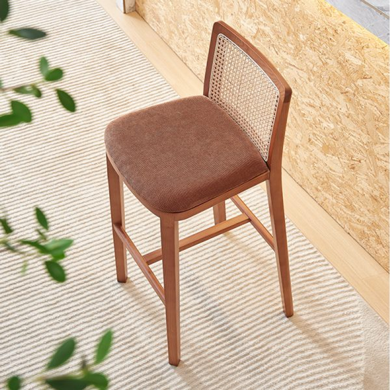 A stylish wooden bar stool with a rattan backrest and cushioned seat, perfect for bar and kitchen spaces.