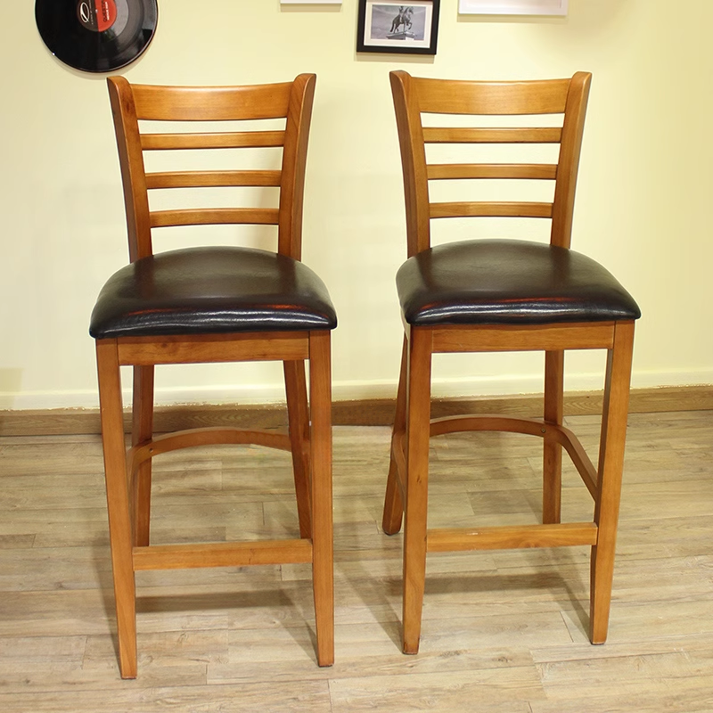 A pair of wooden bar stools with black cushioned seats, placed in a cozy dining environment, perfect for commercial use.