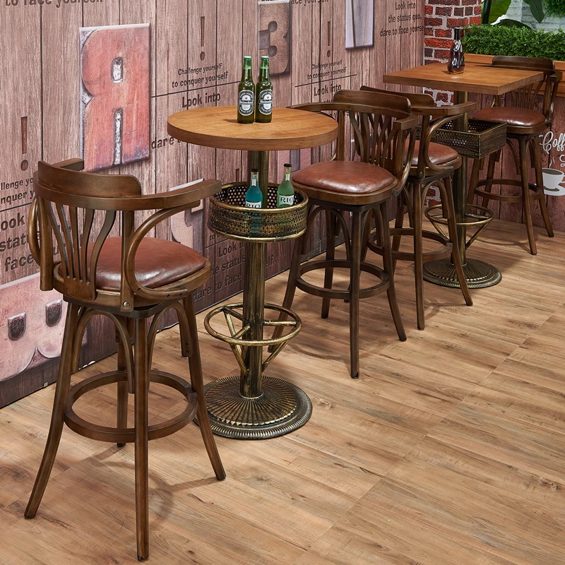 Set of wooden bar stools with leather seats placed around a bar table in a rustic setting.