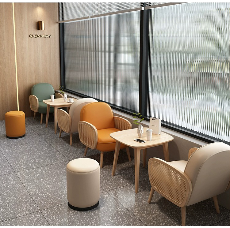 A modern lounge area with rattan armchairs in various colors, minimalist wooden tables, and natural light filtering through textured windows. Ideal for cafes and waiting rooms