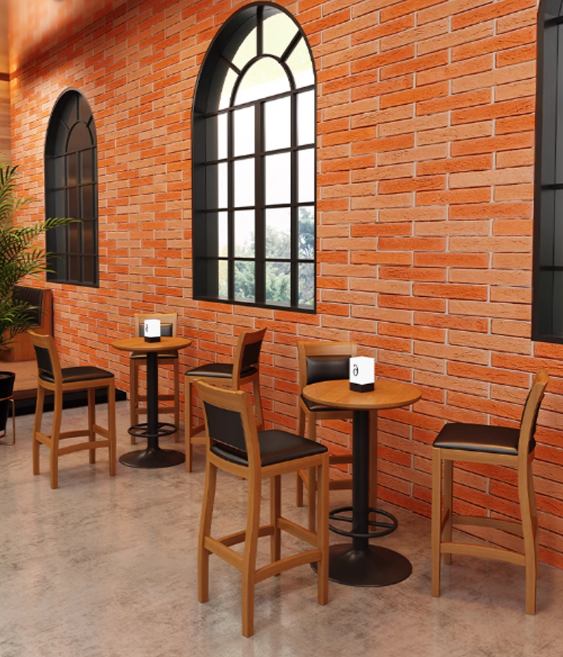 Small round tables with black cushioned chairs in a restaurant with brick walls