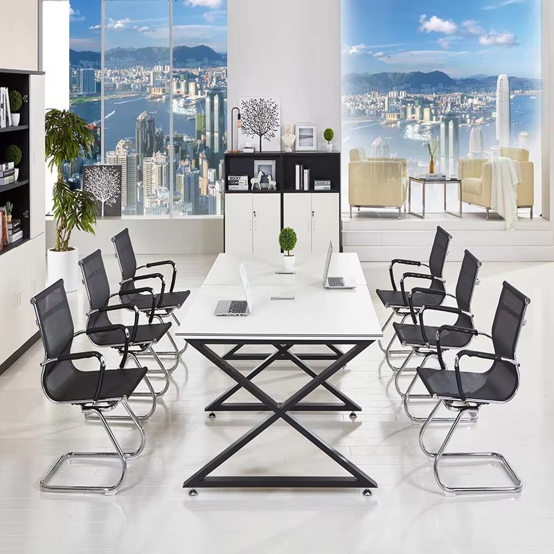 Modern conference room with a long rectangular table, black mesh office chairs, laptops, and large windows