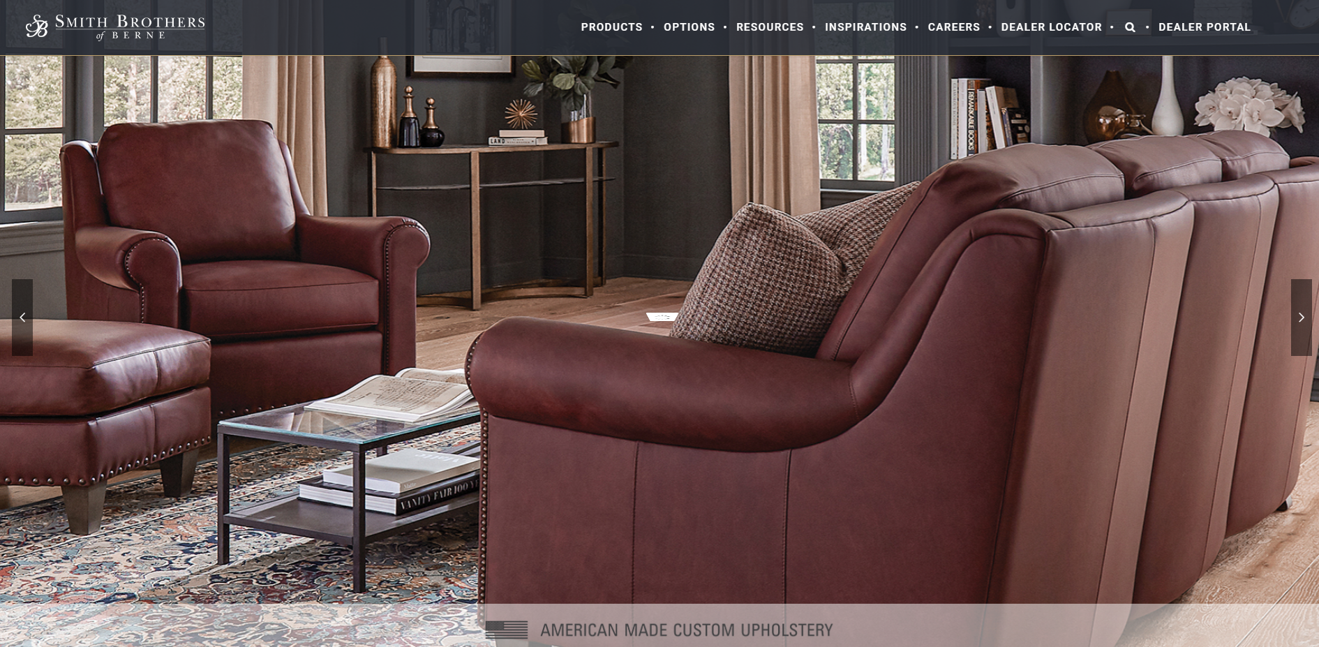 A set of burgundy leather furniture featuring a sofa, armchair, and ottoman with nailhead trim. 