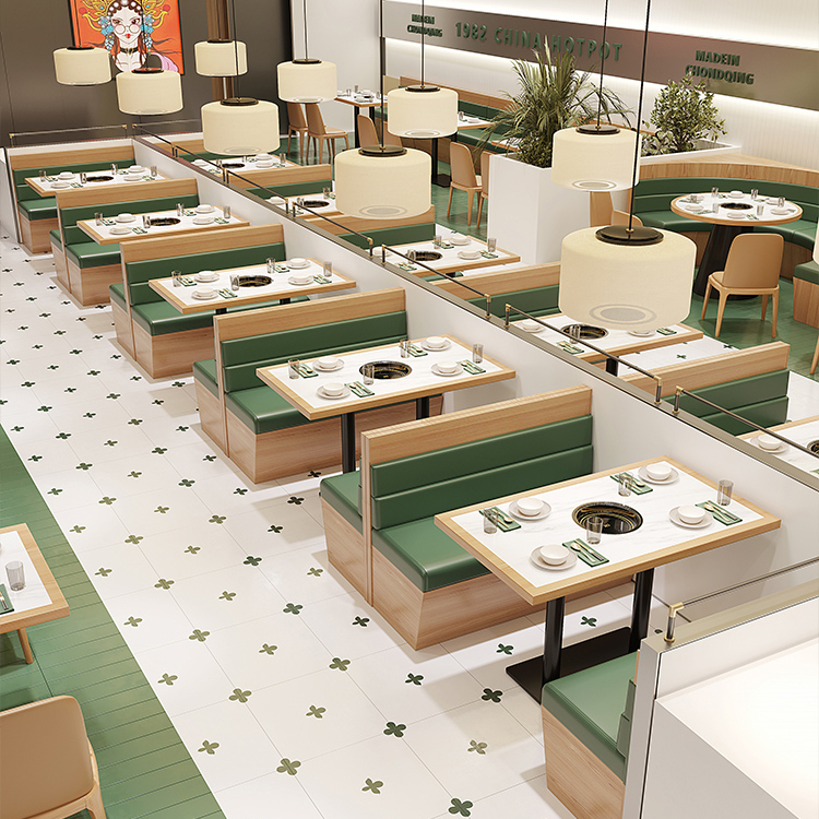 Modern restaurant interior with green booth seating, wooden tables, and sleek pendant lighting.