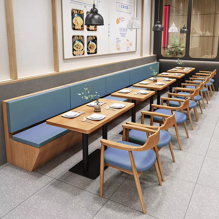 Long booth seating with modern wooden tables and matching blue padded chairs in a contemporary restaurant layout.