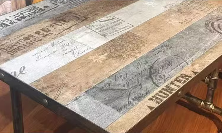 Detailed close-up view of a rustic industrial table featuring wooden panels with distressed finish and stamped designs. 