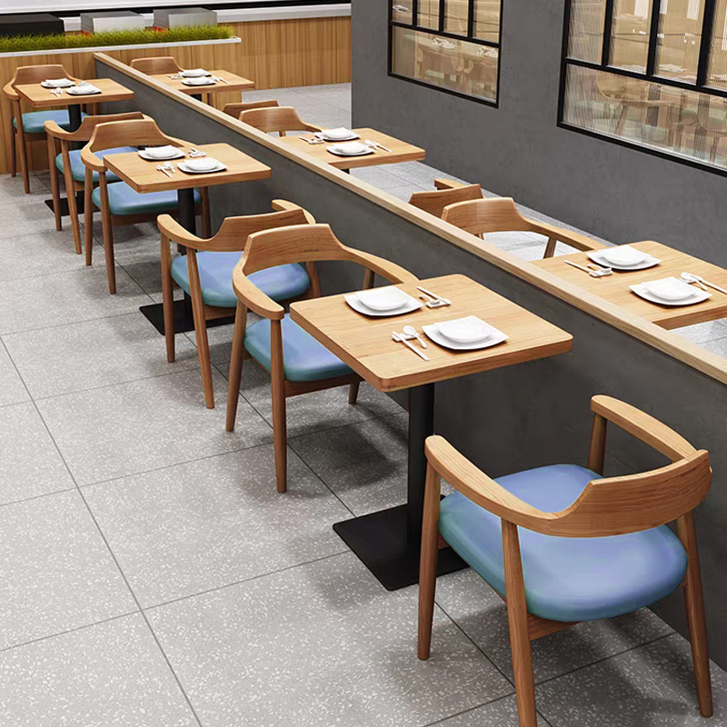 Wooden dining chairs with armrests paired with multilayer wood veneer tables, creating a warm and inviting restaurant setup.