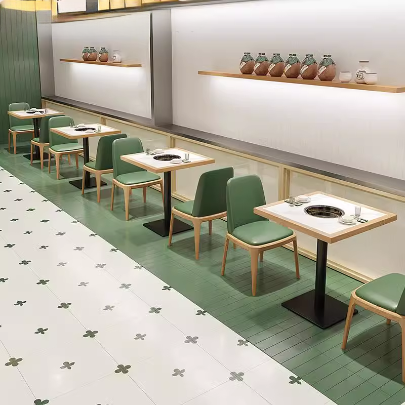 Modern green seating area featuring white marble top tables with bamboo frames, set in a stylish restaurant interior.