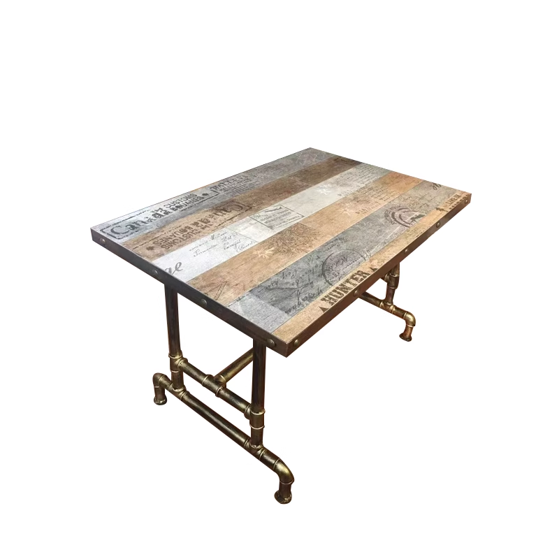 Industrial retro dining table with a multi-color wooden top and pipe legs, featuring an intricate vintage design with printed patterns and brass-colored pipe legs.