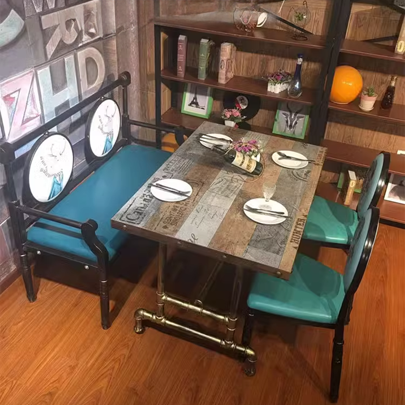 Industrial style table featuring a distressed wooden top with a variety of brown and gray panels, placed in a cozy setting with matching teal chairs.