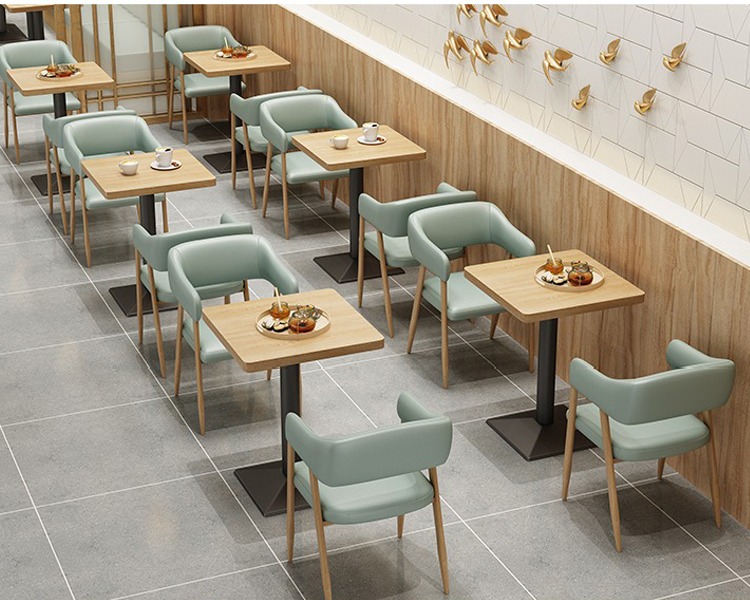  Mint green cafe seating with upholstered chairs and rectangular wooden dining tables against a natural wood wall background.