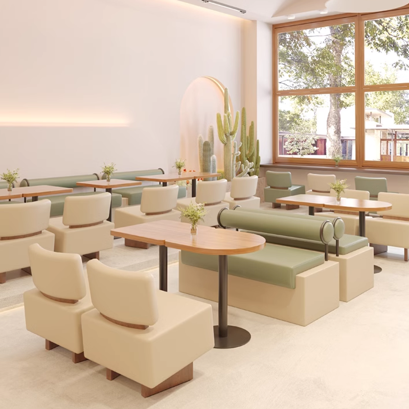 A spacious café interior featuring modern booth seating and wooden tables with green and beige cushioned chairs.