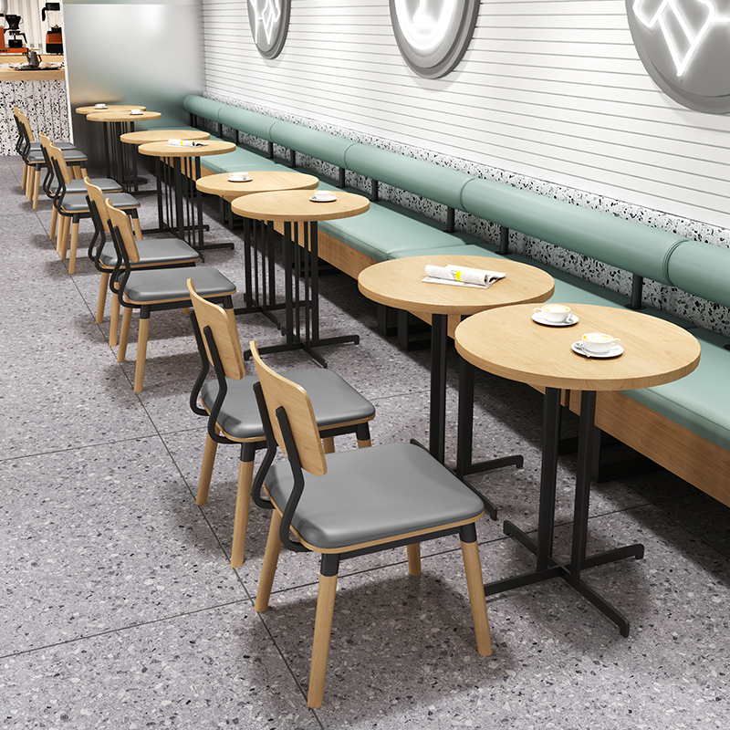  Modern cafe bar table with light green and gray cushioned stools, offering a stylish communal seating arrangement.