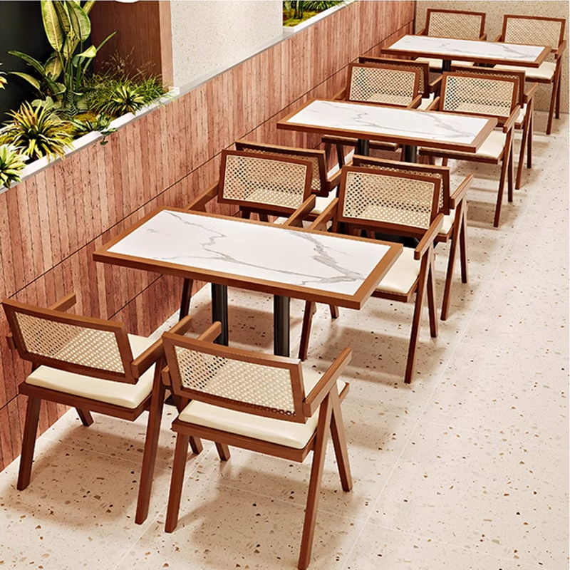 Stylish restaurant seating with cane-back chairs and marble-topped tables, ideal for modern dining areas.