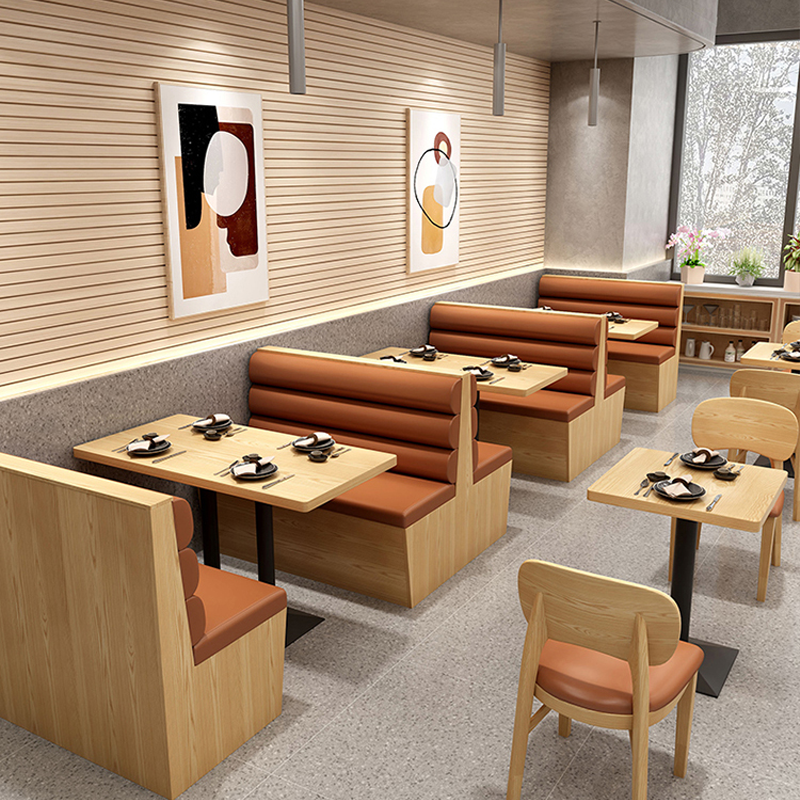 Linear dining layout with wooden booth seating, orange leather cushions, and matching wooden chairs in a cozy restaurant setting.