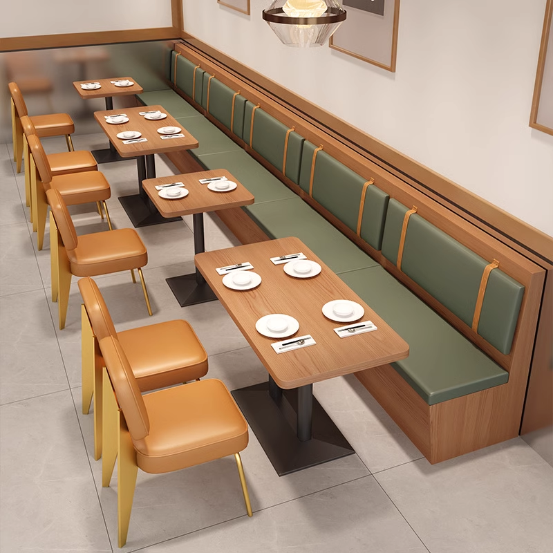 Long wall-mounted booth seating with green cushions, paired with rectangular wooden tables and orange leather chairs in a neat arrangement.