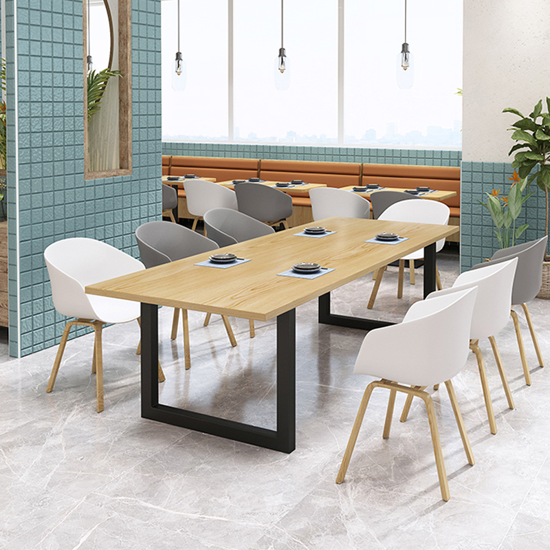 Long wooden dining table with a black metal base, surrounded by modern white and grey shell chairs