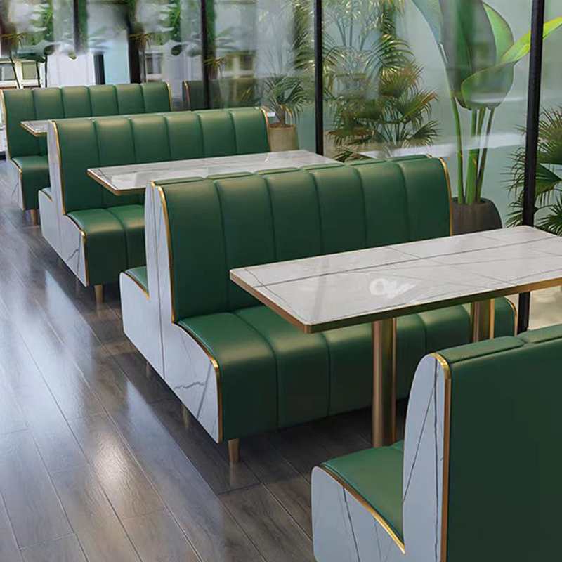 Luxury restaurant booths with green upholstery and marble-patterned side panels.