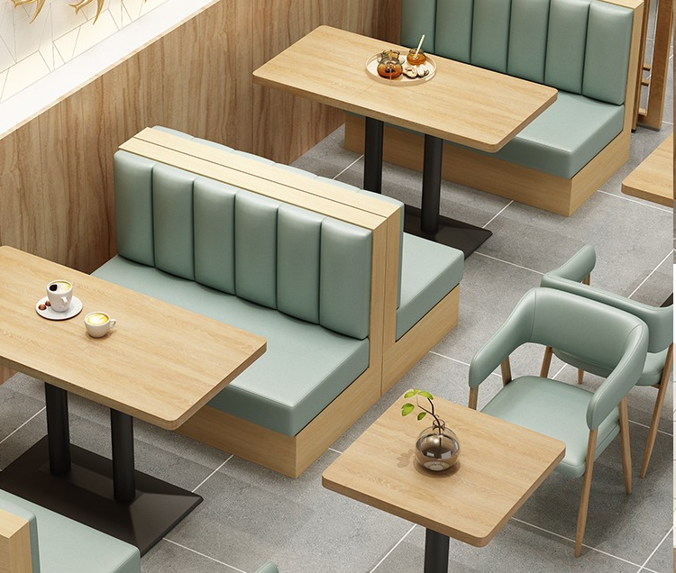 Modern cafe seating arrangement with light green upholstered booths and wooden tables for a cozy dining experience.