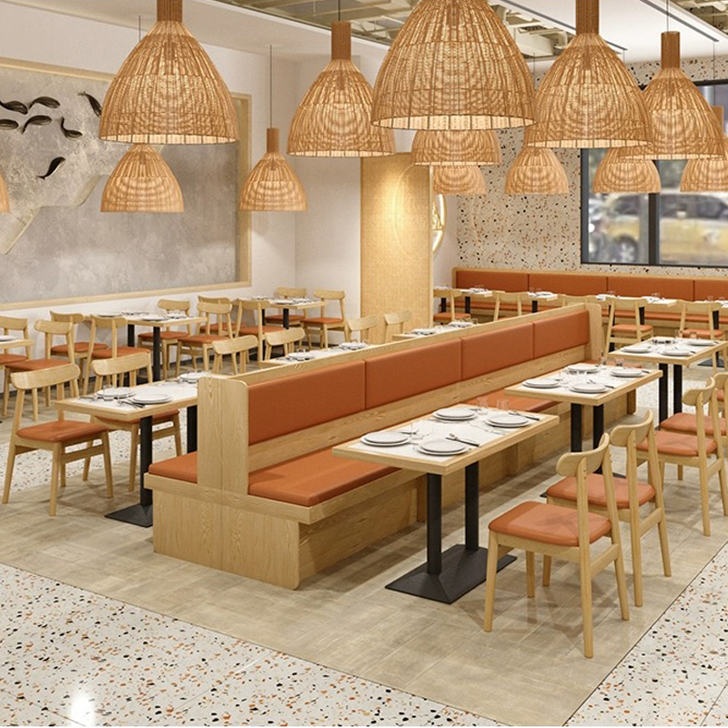 Modern dining area with light wooden furniture, orange cushions, and ample natural light, featuring an open layout for restaurants.