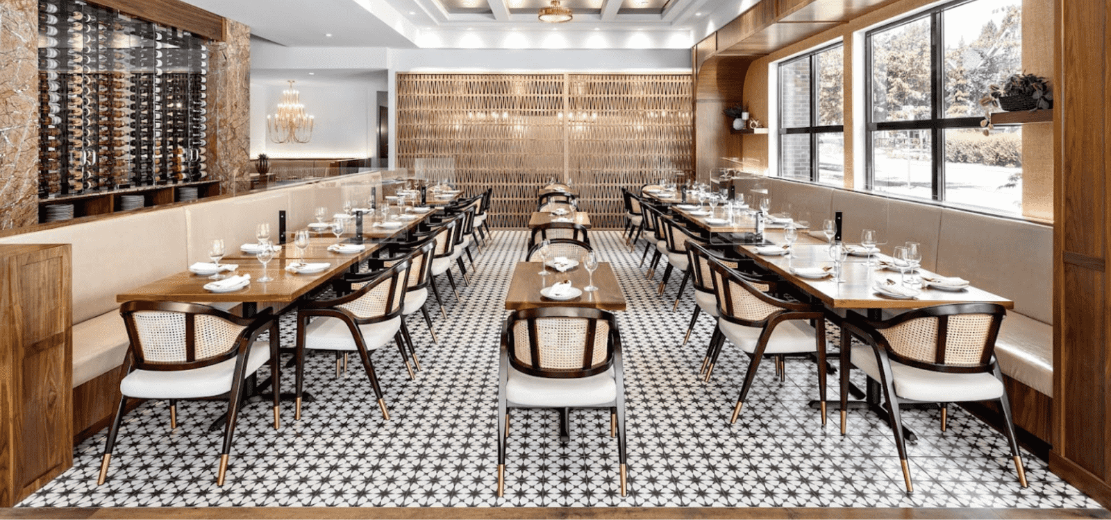 Elegant restaurant interior featuring wooden dining chairs with rattan backrests, long wooden tables, and a sophisticated wine display wall.