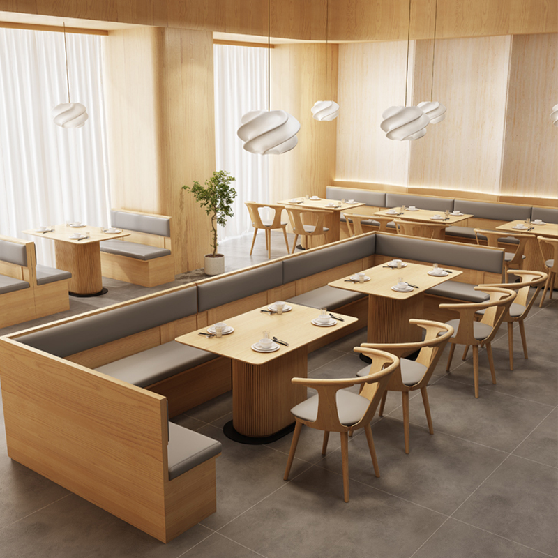 Minimalistic dining layout with light wooden furniture, including rectangular tables and cushioned bench seating, complemented by contemporary lighting.