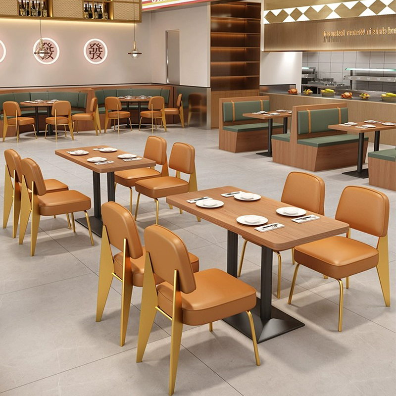  Modern restaurant interior featuring rectangular wooden tables, orange leather chairs with gold frames, and green cushioned booth seating.