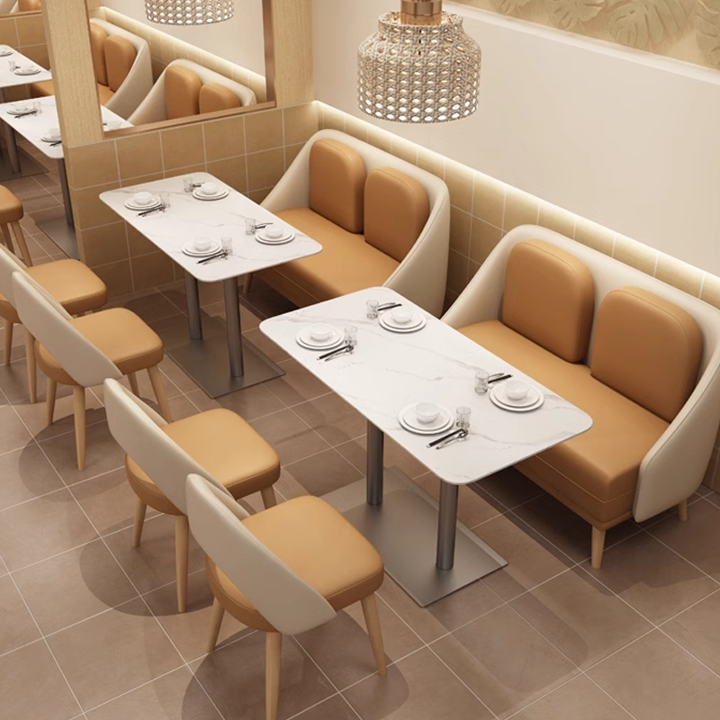 Modern restaurant interior with beige cushioned seating, slate tables, and elegant pendant lighting, designed for a cozy dining experience.