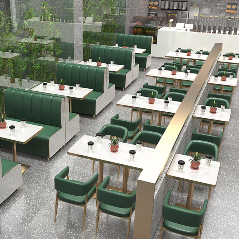 Elegant restaurant interior featuring modern green seating, marble tables, and lush decor.