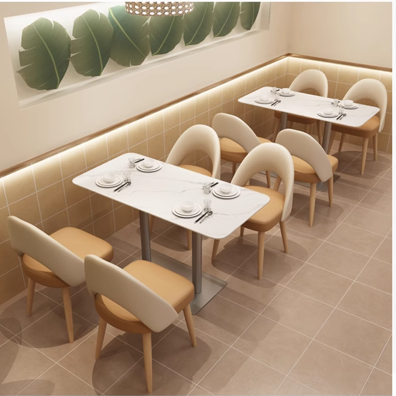 Modern white marble dining table with metallic base and comfortable beige dining chairs, ideal for cafe and restaurant settings