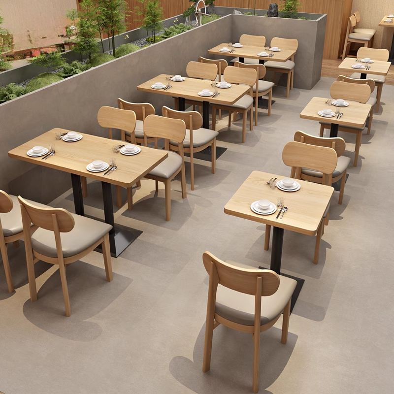 dining tables and light wooden chairs with beige cushioned seating at a modern restaurant.