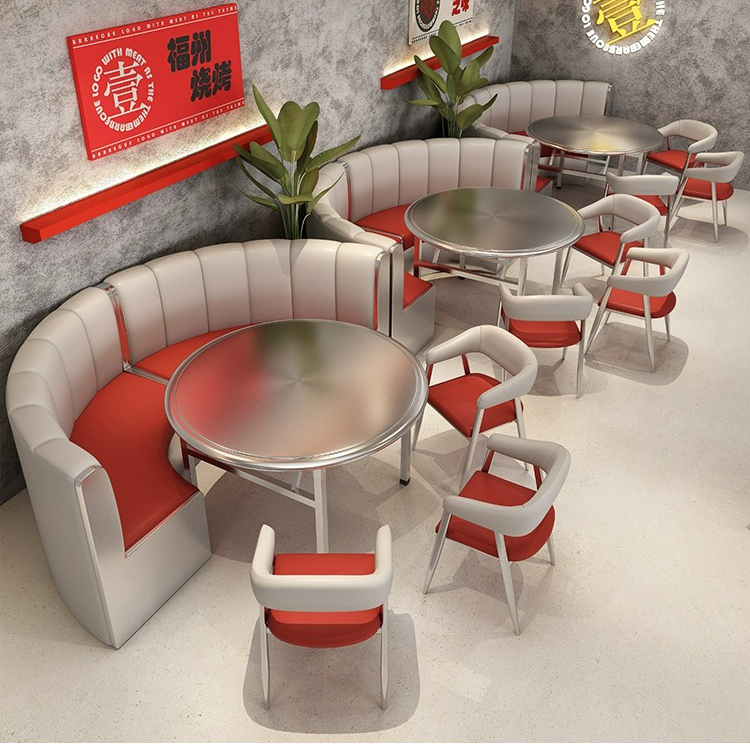 Curved booth seating with red and white design surrounding a round steel dining table.