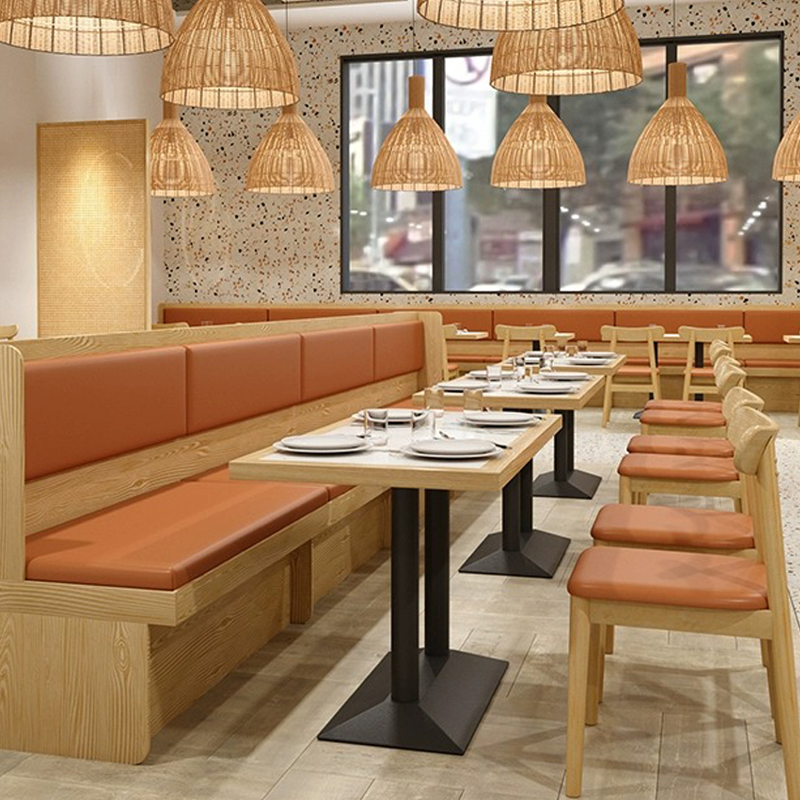 Restaurant dining area with light wooden chairs, orange cushioned seats, and matching wooden tables set for guests.