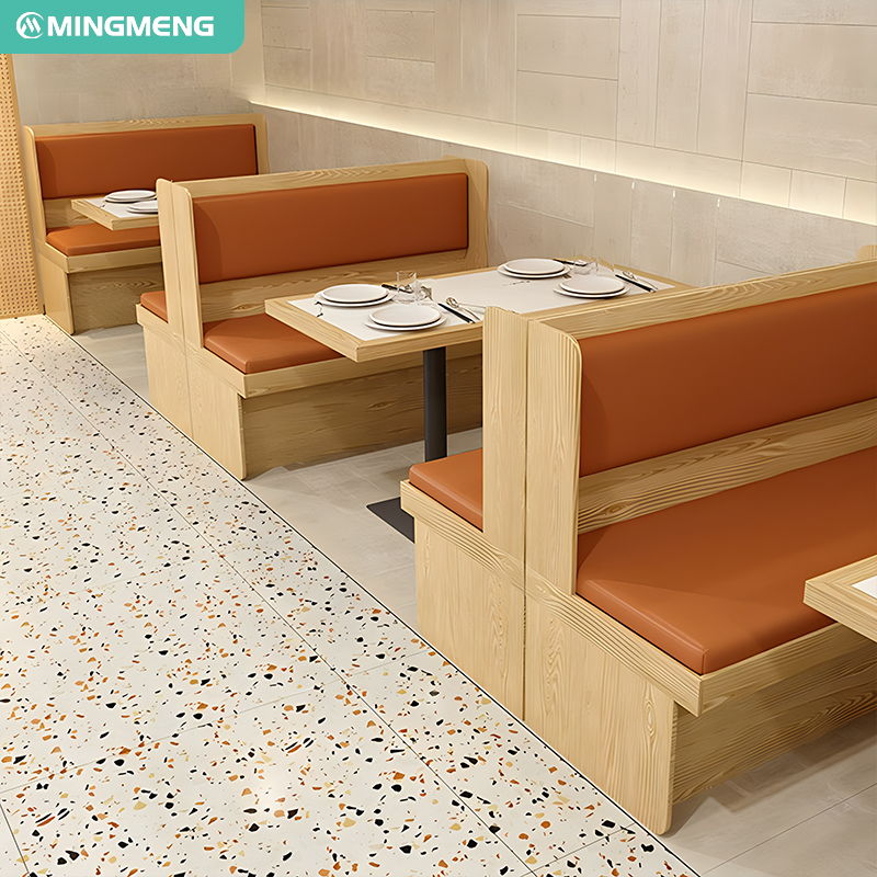 Restaurant booth seating with wooden benches and orange cushions, paired with neatly set dining tables, modern dining furniture design.