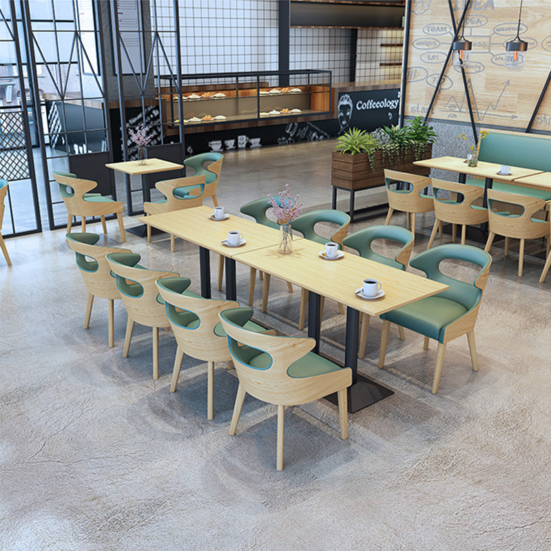 Modern dining seating with green cushions, wooden tables, and soft lighting, ideal for cafes or contemporary restaurants.