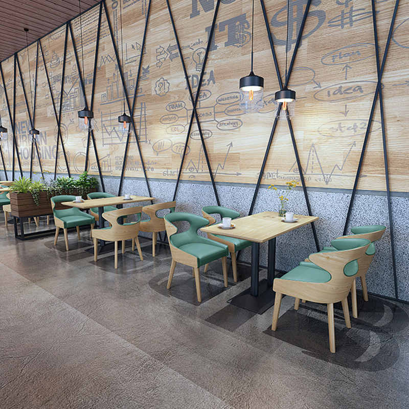 Contemporary restaurant seating with green cushions, wooden tables, and industrial-style wall decor, ideal for modern dining spaces.