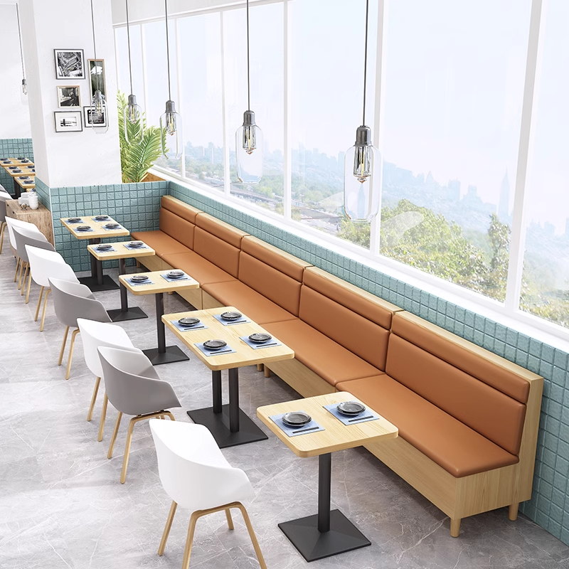 Restaurant seating with a long booth featuring brown leather cushions and paired with modern white and grey shell chairs.