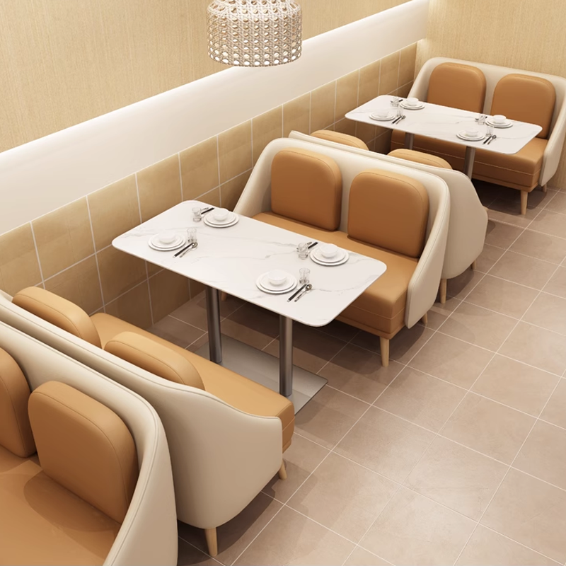 Wall-aligned dining layout with two-seater sofas, marble-top tables, and comfortable chairs.