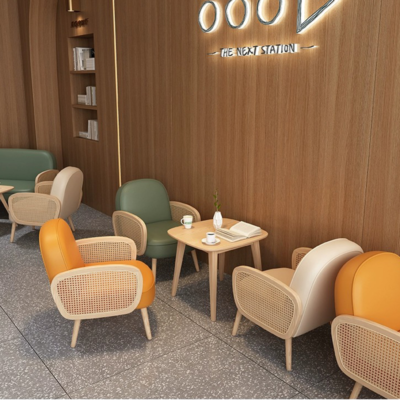 A stylish café setup with wooden furniture and soft lighting, featuring a mix of orange, green, and white chairs around light wood tables.