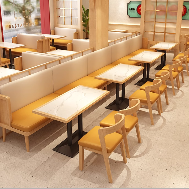 Cozy restaurant booths with yellow chairs and white marble tables.