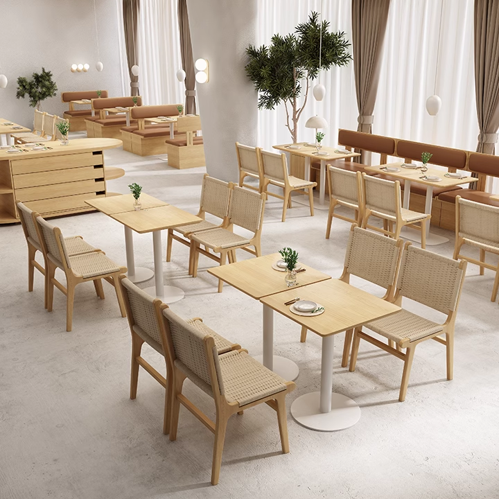 Dining area featuring light-colored tables, chairs with woven backs, and soft seating booths.